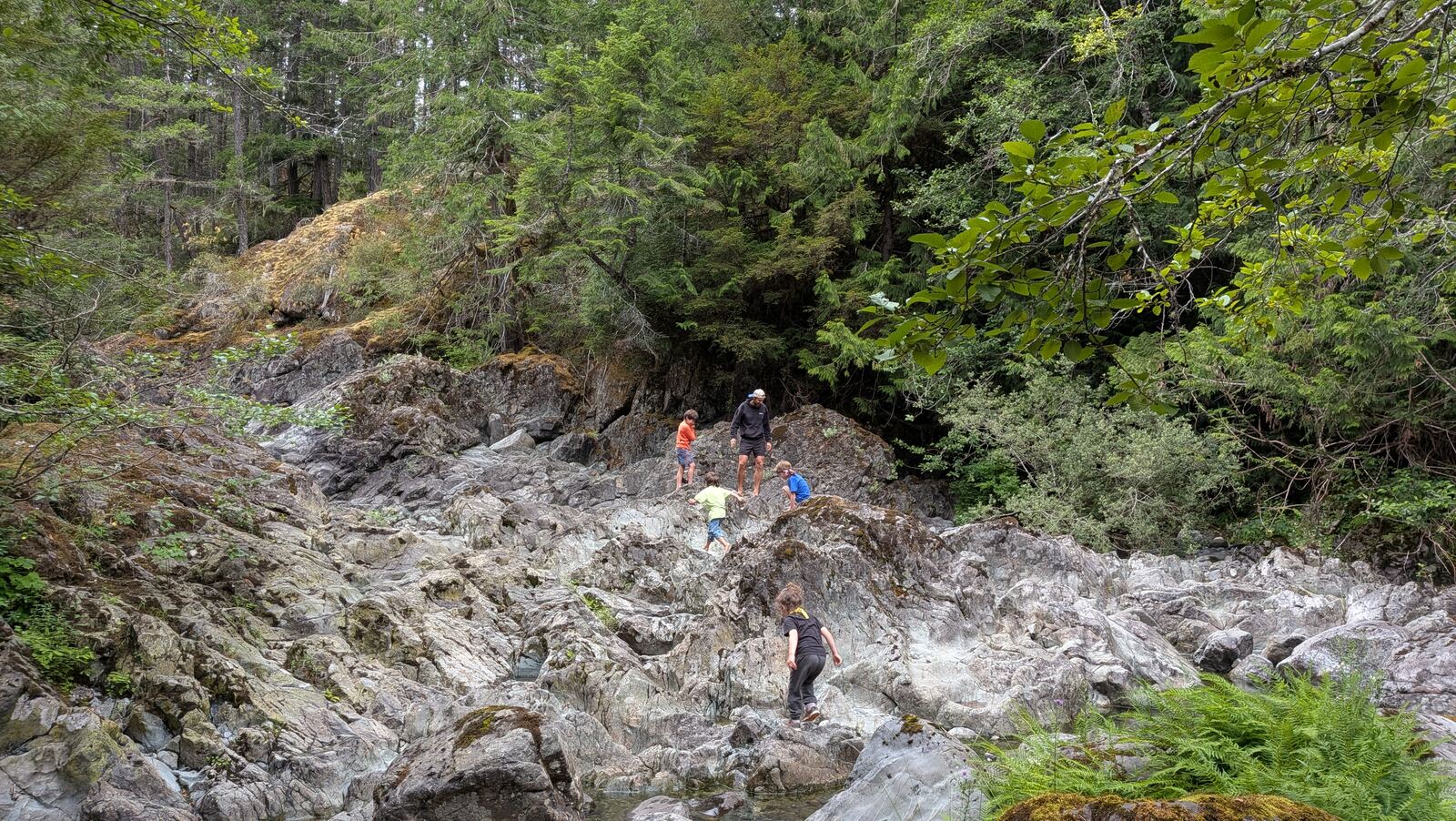 A rocky creek canyon with people exploring in the distance