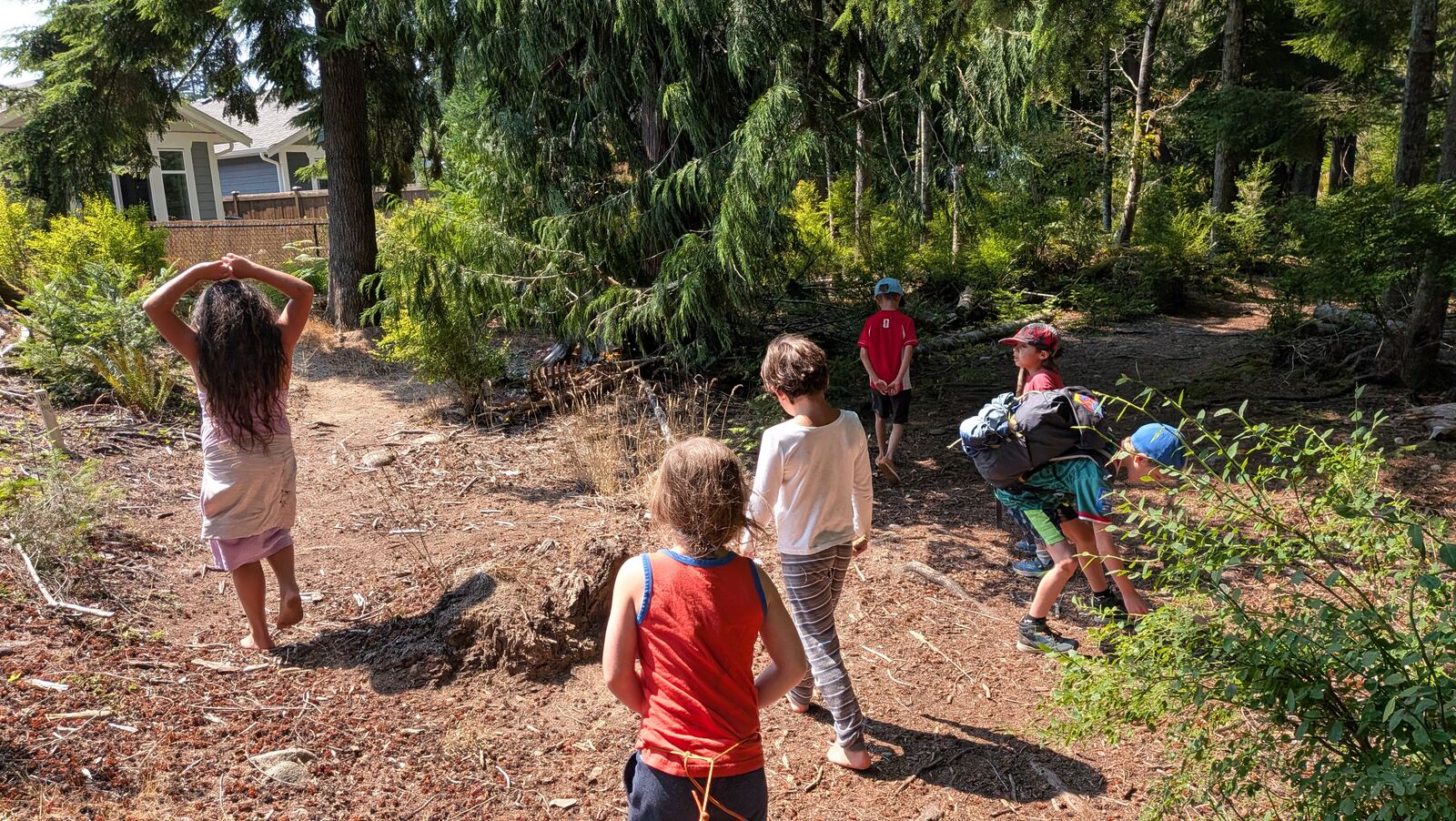 Children walking through the forest, one balancing a basket on their head