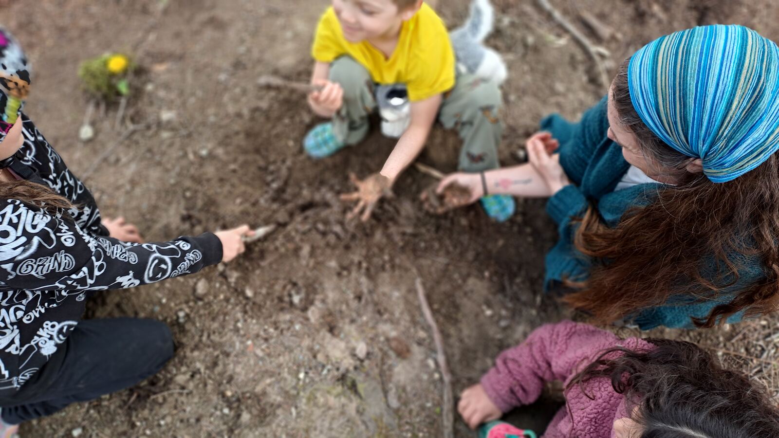Mentors and children gathered together over an activity on the ground