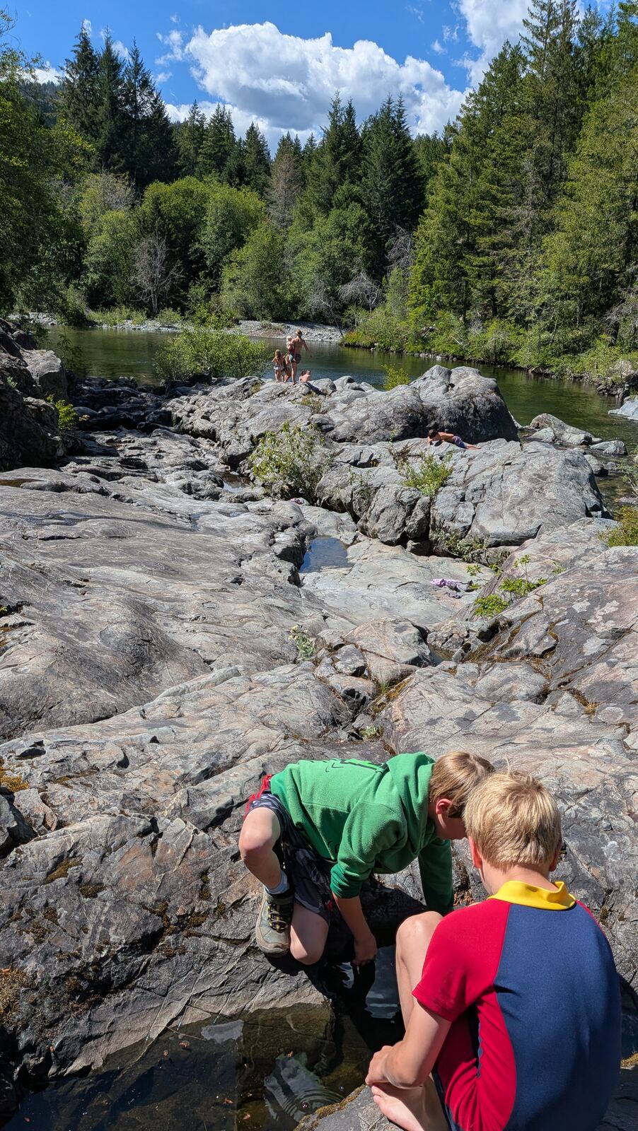 Children scrambling over large smooth river rocks