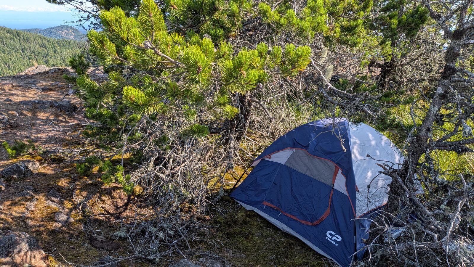 A small tent pitched alone on a rocky cliff overlook